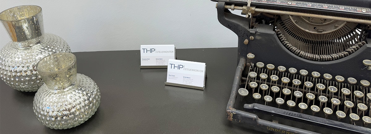 Schreibtisch mit Visitenkarten der THP Steuerkontor und einer alten Schreibmaschine
